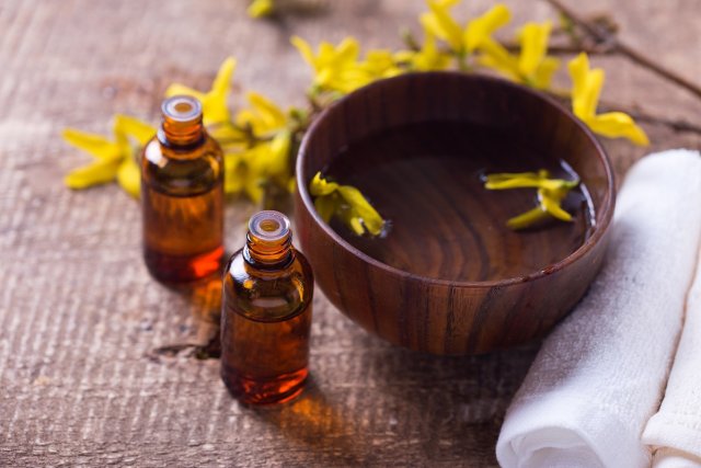 Spa setting. Essential aroma oil , water in bowl, towels, yellow flowers on aged wooden background. Selective focus. 